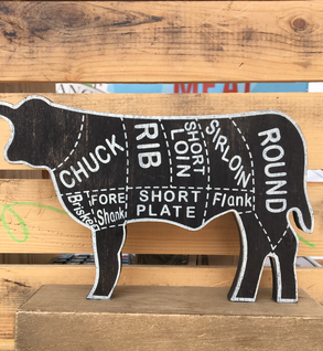 Assorted cuts of raw beef, including ribeye and tenderloin, displayed on a wooden cutting board with fresh rosemary, a mortar and pestle, and a bowl of sea salt, highlighting gourmet cooking ingredients.