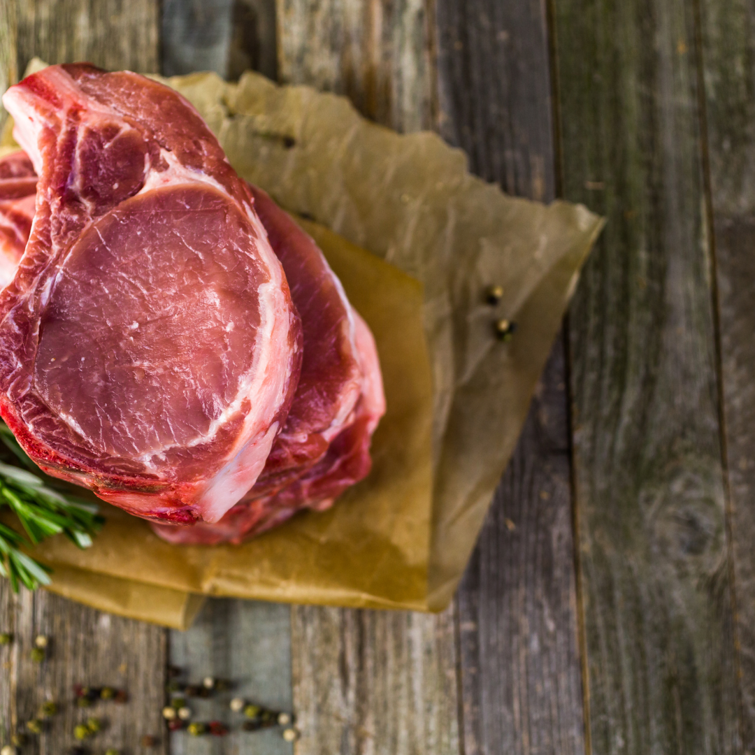 Assorted cuts of raw beef, including ribeye and tenderloin, displayed on a wooden cutting board with fresh rosemary, a mortar and pestle, and a bowl of sea salt, highlighting gourmet cooking ingredients.